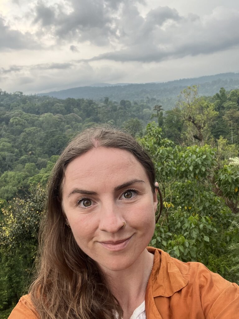 Sally in Coorg, India, surrounded by lush jungle greenery, reflecting on spirituality, energy healing, and Eastern philosophy