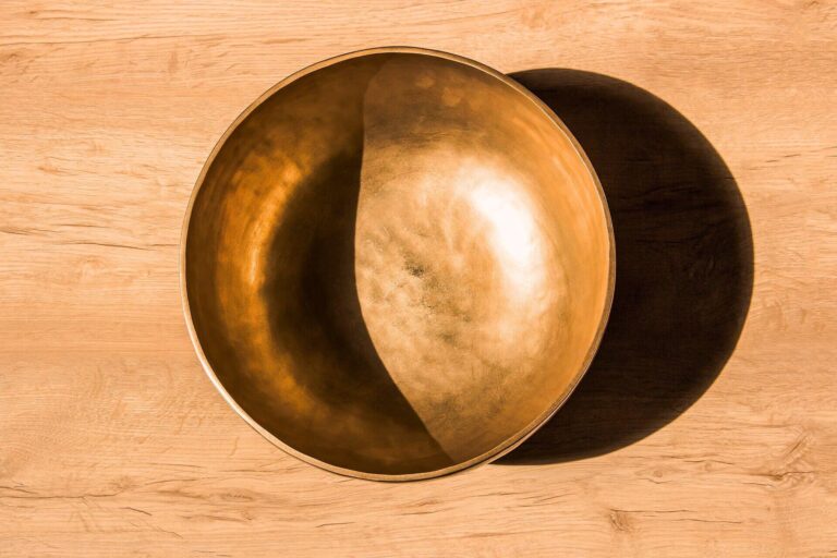 Birds-eye view of a Himalayan singing bowl with shadows creating a yin-yang or moon-like effect, representing meditation, inner balance, and surrender.